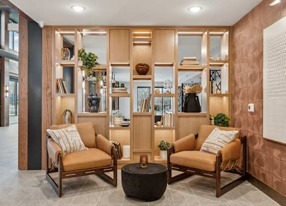 A living room with a brown sofa and a wooden bookshelf.