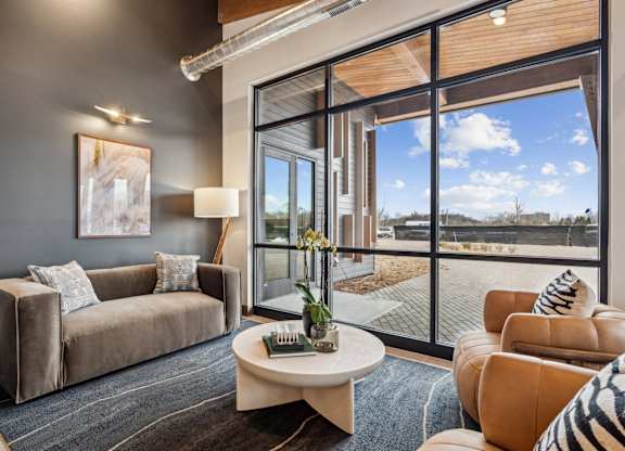 A living room with a grey couch, a coffee table, and a large window.