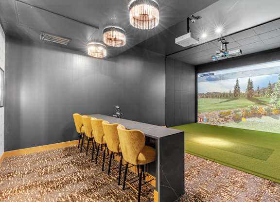 A room with a long table and chairs with a screen at the end of the table.