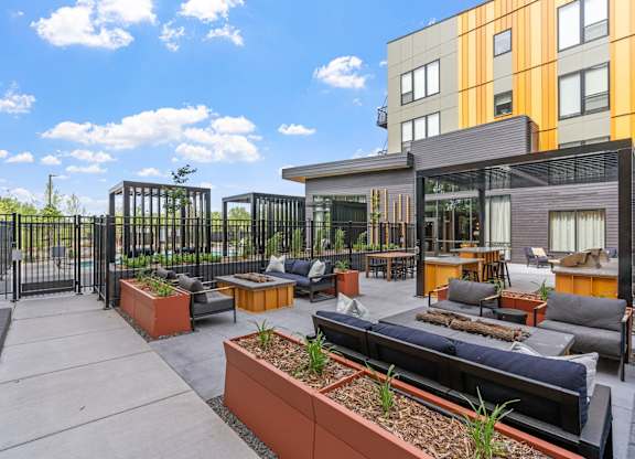 A modern outdoor seating area with a black metal fence and orange planters.