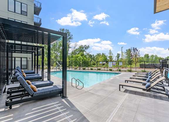A pool area with sun loungers and a building in the background.