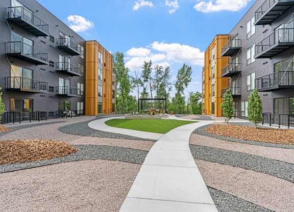 A modern apartment complex with a central walkway and landscaped gardens.