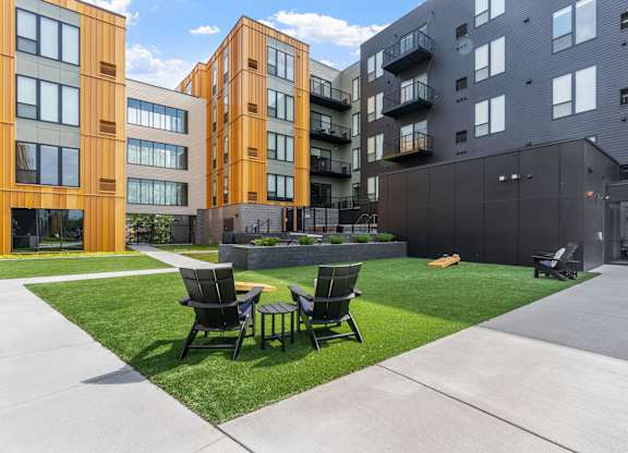 Two chairs are on a lawn in front of a building.