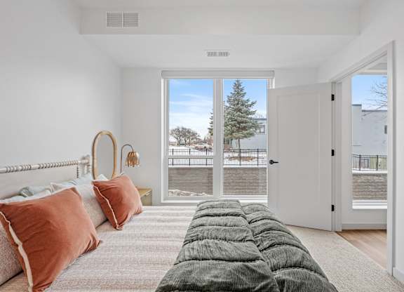 A bedroom with a large bed and a view of the outdoors through a sliding glass door.