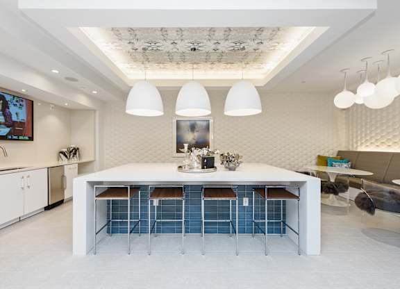 A modern kitchen with a white table and blue chairs.