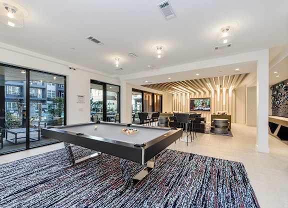 A pool table is in the middle of a room with a blue rug.