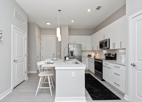 A white kitchen with a black rug on the floor.