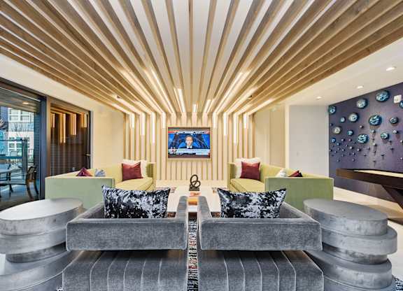 A modern living room with a grey sofa and a wooden ceiling.