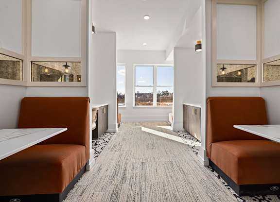 A long, narrow room with orange booths and a carpeted floor.