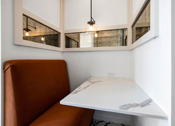 A brown leather sofa sits under a white table with a marble top.
