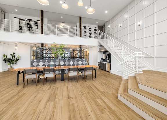 A white interior with a staircase and a long table with chairs.