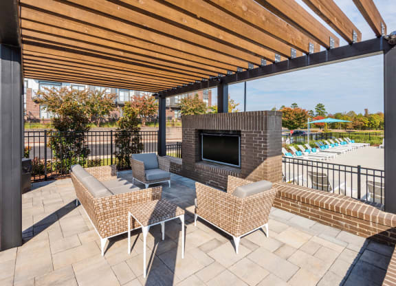 a patio with a fireplace and chairs and a pool