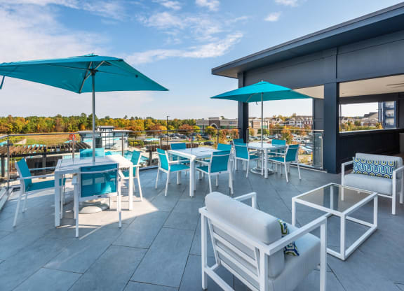 a rooftop patio with tables and chairs and umbrellas