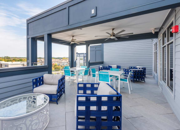 a covered patio with blue chairs and tables and a jacuzzi