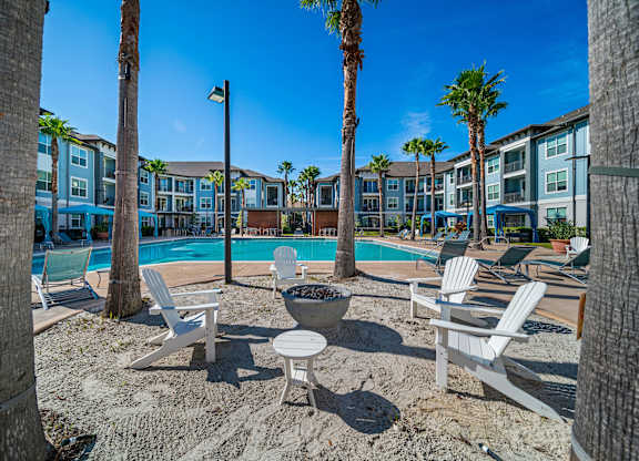 A pool surrounded by palm trees and chairs.