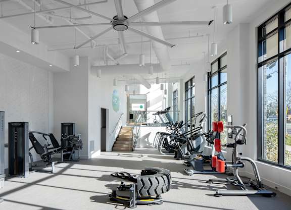 A gym with a variety of equipment including treadmills, weights, and exercise bikes.