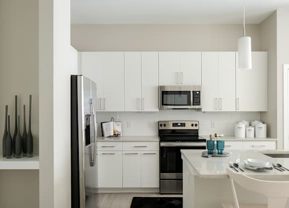 A modern kitchen with white cabinets and appliances.