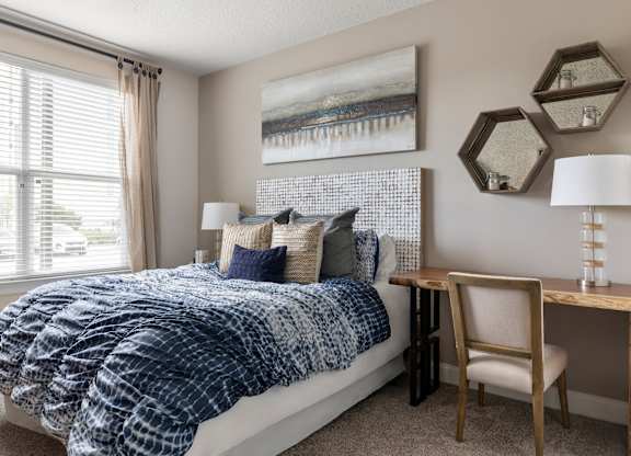 A bedroom with a bed, chair, and a painting on the wall.