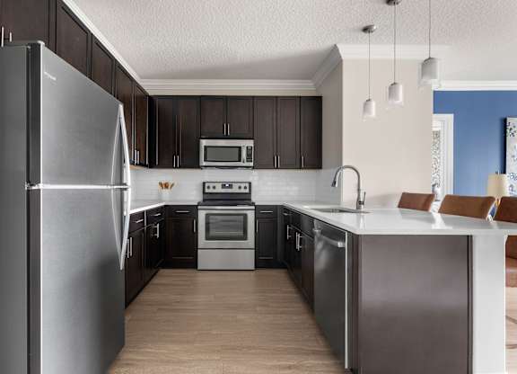 A modern kitchen with dark wood cabinets and stainless steel appliances.