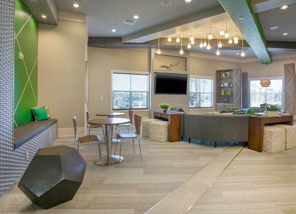 A modern office space with a green accent wall and a variety of seating options.
