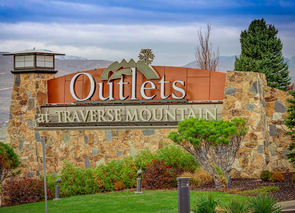 A sign that says Outlets at Traverse Mountain in front of a mountain.