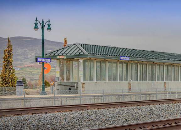 A train station with a green roof and a mountain in the background.