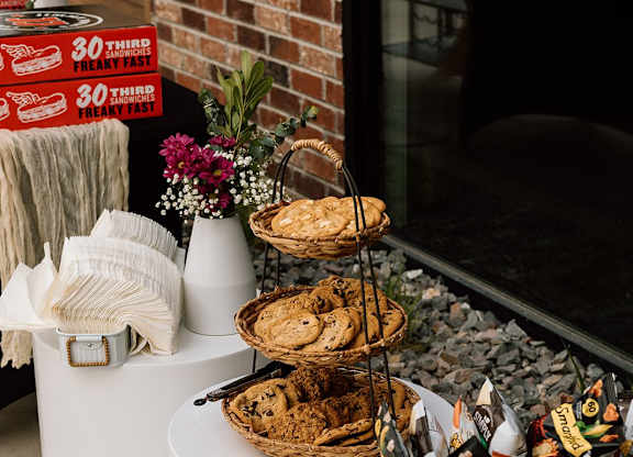 A basket of snacks sits on a table next to a sign that says