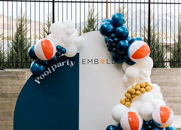 A pool party balloon arch with the words