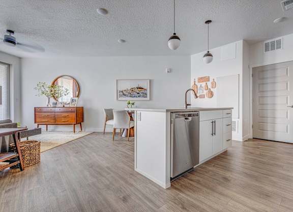 A modern kitchen with white cabinets and a wooden floor.