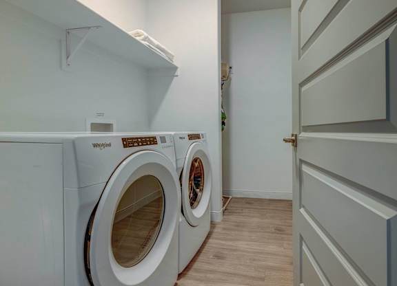 A Whirlpool washing machine is in a small laundry room.