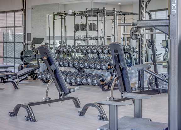 A gym with a variety of equipment including dumbbells and weight machines.