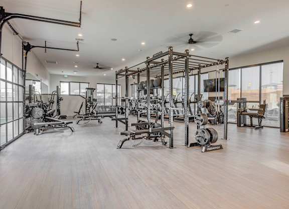 A spacious gym with a variety of equipment and a ceiling fan.