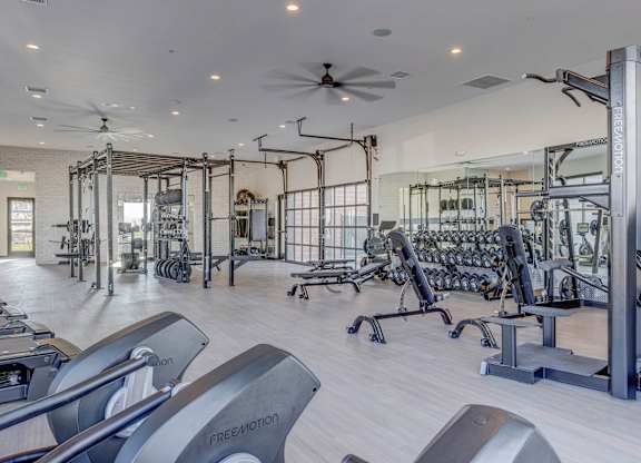 A gym with a variety of equipment including treadmills, weights, and a rowing machine.