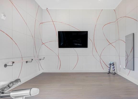 A bathroom with a white tiled wall and a television mounted on it.