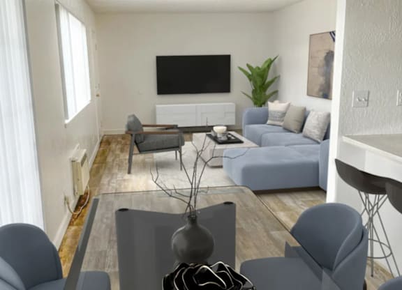 A living room with a grey sofa, grey armchairs, a grey coffee table, a flat screen TV, and a plant.