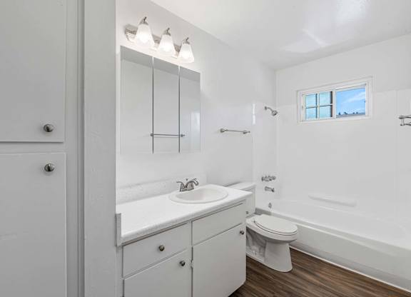 A white bathroom with a toilet, sink, and mirror.