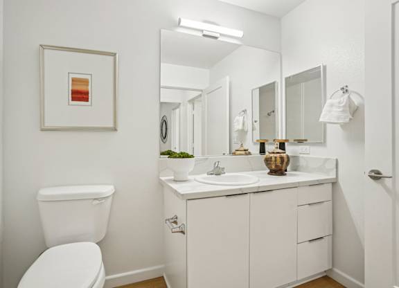 A white bathroom with a toilet, sink, and mirror.