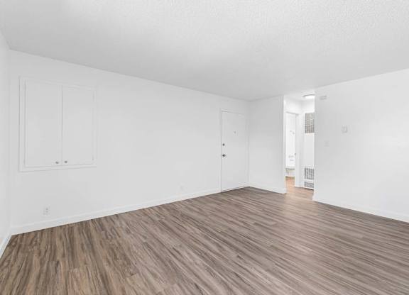 A room with wooden flooring and white walls.
