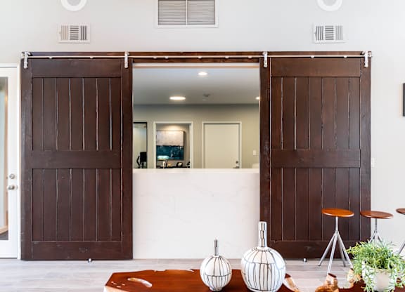 A white room with a brown door and a white table with a plant on it. at Chaparral Apartments, Palmdale, CA