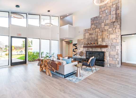 A living room with a stone fireplace and a couch at Chaparral Apartments, California, 93551