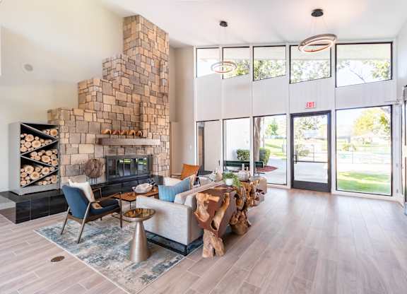 A modern living room with a stone fireplace and a blue rug at Chaparral Apartments, Palmdale, California