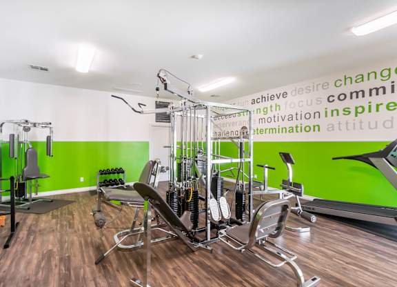 A gym with a green wall and a row of exercise machines at Chaparral Apartments, Palmdale