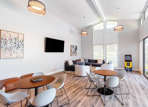 A modern living room with a wooden table and white chairs at Chaparral Apartments, Palmdale, CA, 93551