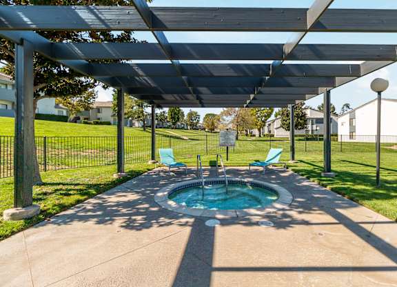 A hot tub is under a canopy in a backyard at Chaparral Apartments, Palmdale