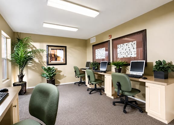 A room with a desk, chairs, and computers.