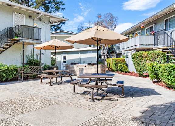 A patio with tables and chairs and umbrellas.