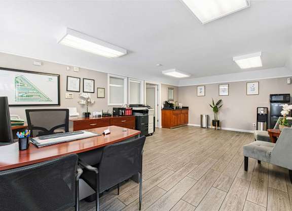 A well-lit office space with a desk, chairs, and a computer.