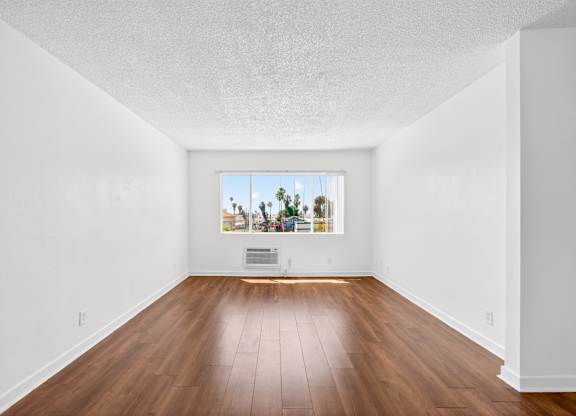 A room with a wooden floor and a picture on the wall.