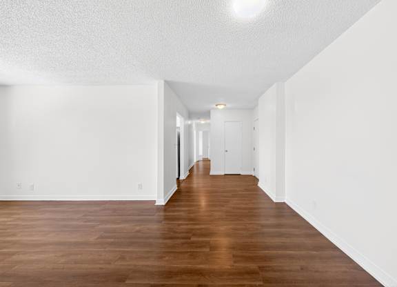 A long hallway with wood floors and white walls.