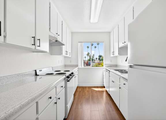 A kitchen with white cabinets and a view of the outdoors.